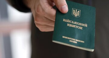 Людина тримає військовий квиток в руці